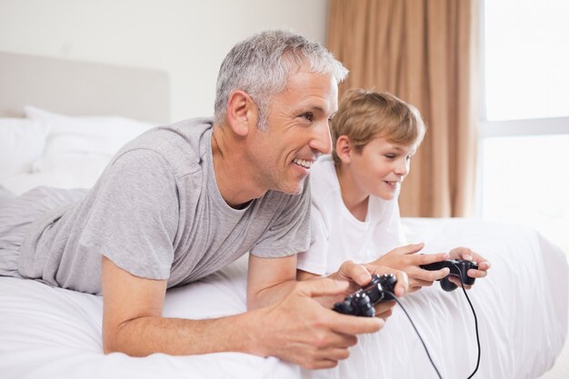 Sonriente padre y su hijo jugando videojuegos