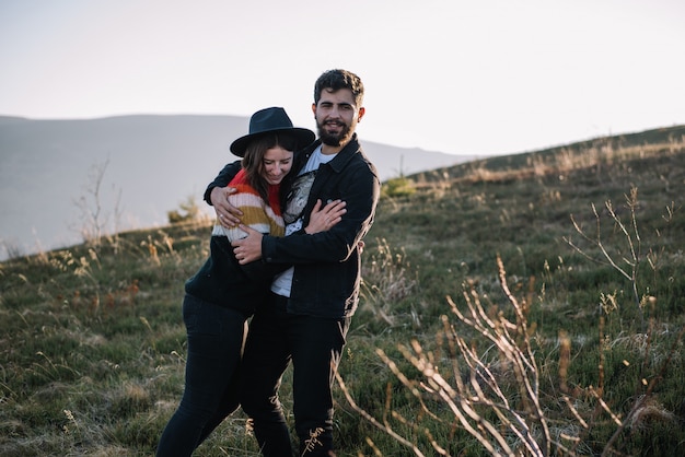 Sonriente pareja abrazándose en el contexto de las montañas de otoño