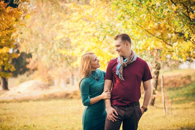 Sonriente pareja abrazándose en el parque otoño