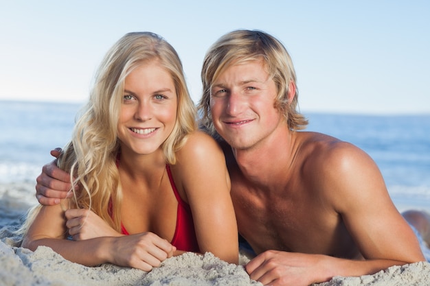 Sonriente pareja acostada en la playa