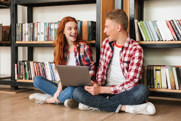 Sonriente pareja de adolescentes sentados en el suelo