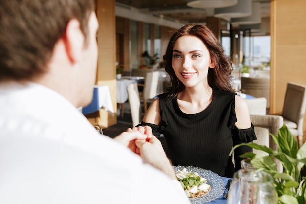 Sonriente pareja amorosa sentada en un restaurante en el interior