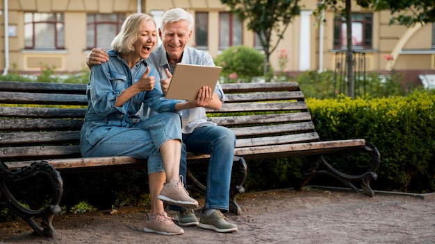 Foto sonriente pareja de ancianos al aire libre con tableta