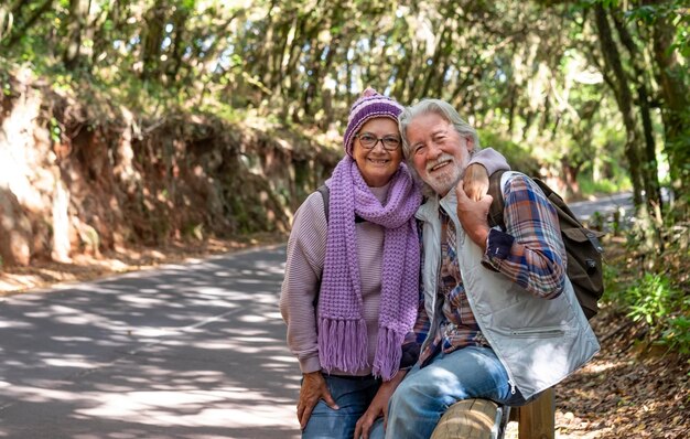Sonriente pareja de ancianos de pelo blanco mirando a la cámara disfrutando de una excursión a la montaña en un día de invierno Personas mayores jubiladas activas y concepto divertido