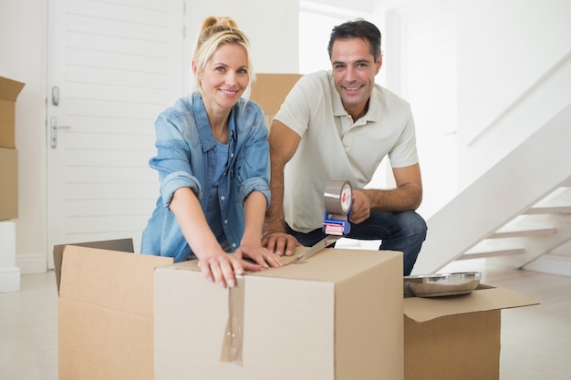 Sonriente pareja cajas de embalaje en una casa nueva