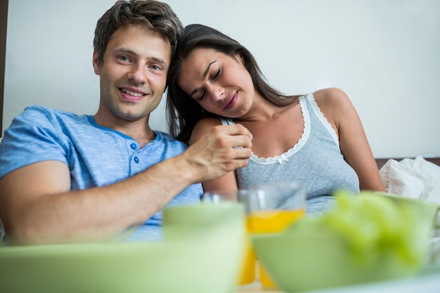 Sonriente pareja desayunando en la cama