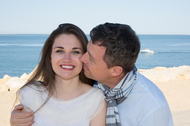 Sonriente pareja joven a cuestas en la hermosa playa de verano