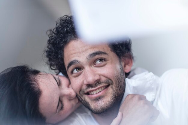 Sonriente pareja joven juntos en la cama con una tableta