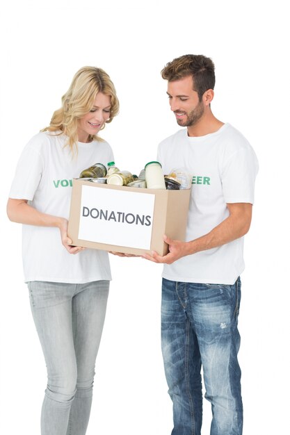 Sonriente pareja joven llevando caja de donación