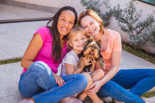 Sonriente pareja de lesbianas con cachorro de niño y mascota. Pareja de lesbianas sosteniendo con su hija adoptiva, concepto de adopción.