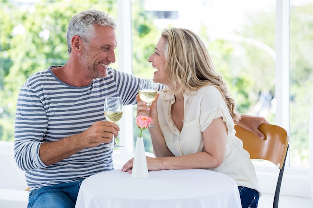 Sonriente pareja madura discutiendo mientras toma vino