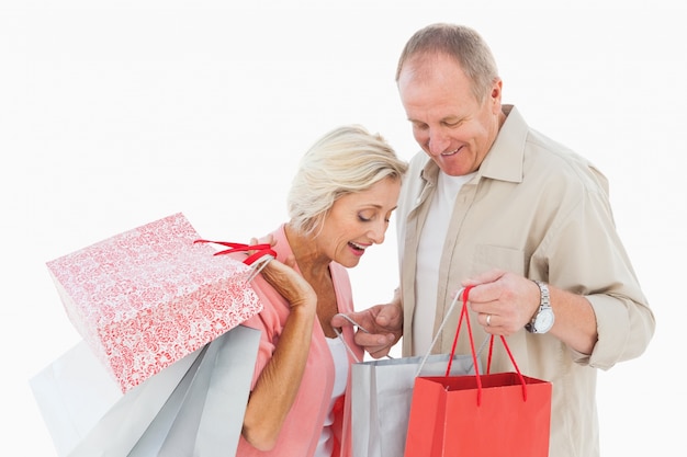 Sonriente pareja madura sosteniendo bolsas de compras