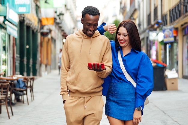 Sonriente pareja multirracial mirando imágenes en el teléfono