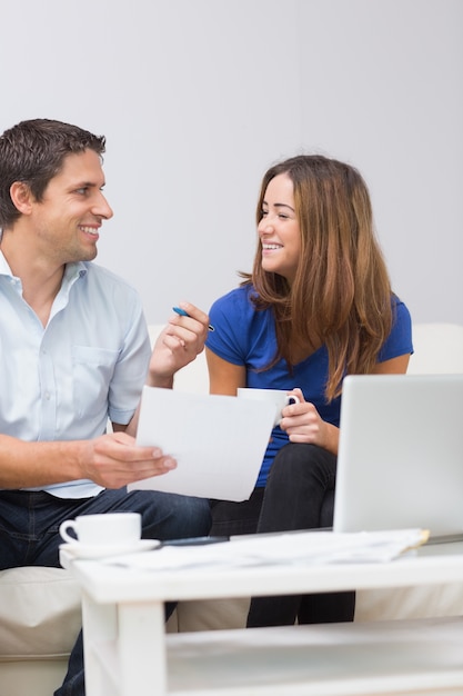 Sonriente pareja pagando sus cuentas en línea en casa