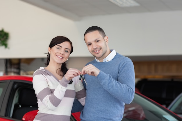 Sonriente pareja de pie junto a un coche