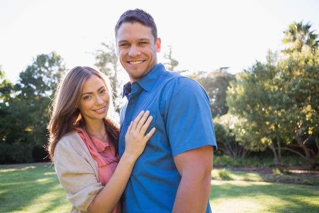 Sonriente pareja de pie en un parque