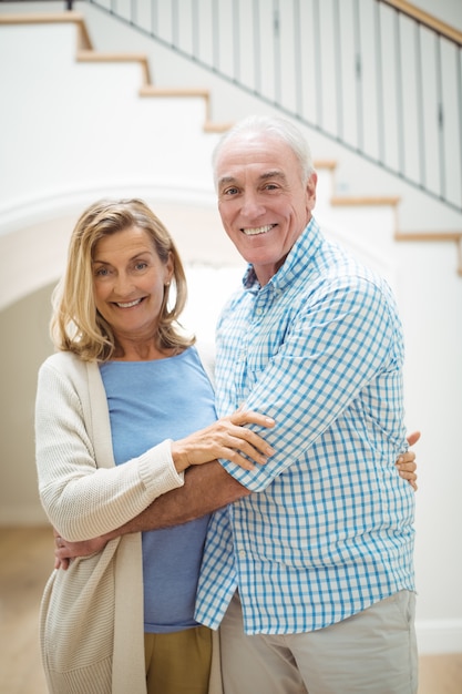 Sonriente pareja senior abrazándose en la sala de estar