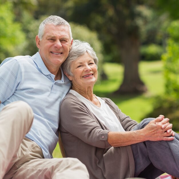 Sonriente pareja senior sentado en el parque