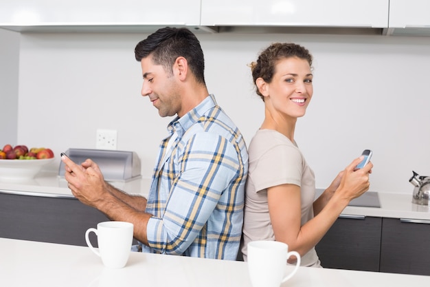 Sonriente pareja sentada de espaldas a los mensajes de texto