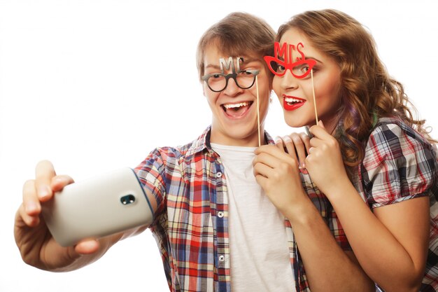 Sonriente pareja con smartphone, selfie y diversión.