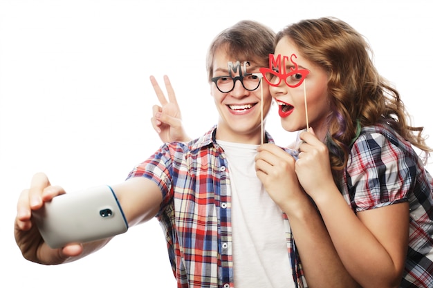 Sonriente pareja con smartphone, selfie y diversión.