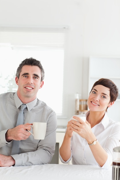 Sonriente pareja tomando café mirando a la cámara