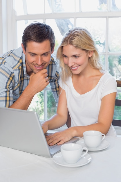 Sonriente pareja usando la computadora portátil en casa