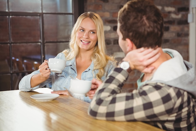 Sonriente rubia disfrutando de café con un amigo