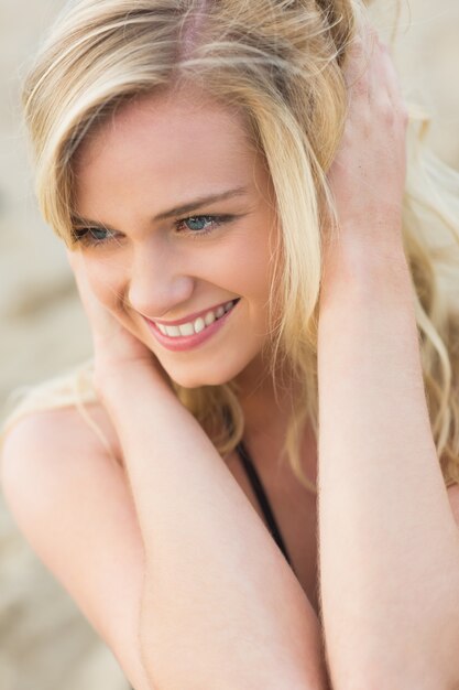 Sonriente rubia joven relajada mirando a la playa