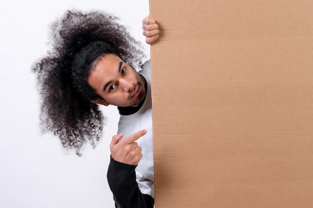 Sonriente sosteniendo un cartel con espacio para copiar y pegar Joven con cabello afro sobre fondo blanco