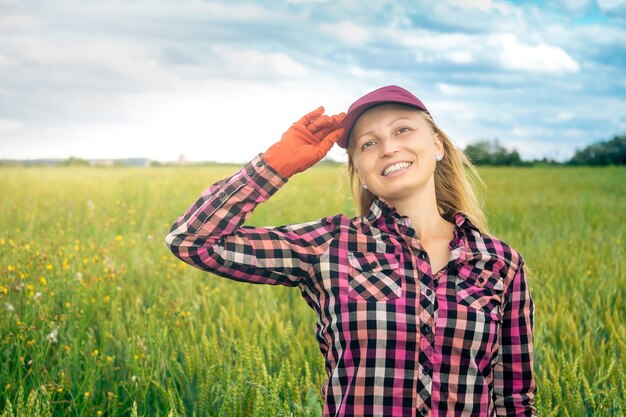 Sonriente trabajadora agrícola en el fondo de un campo de trigo