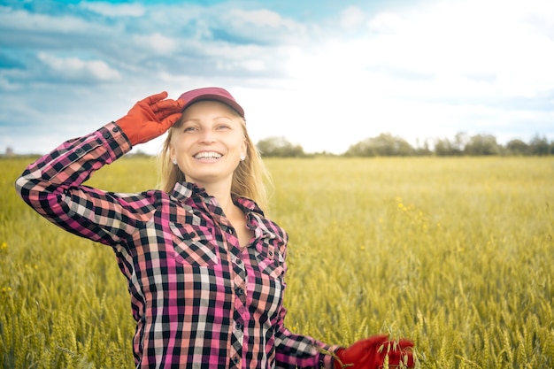 Sonriente trabajadora agrícola en el fondo de un campo de trigo