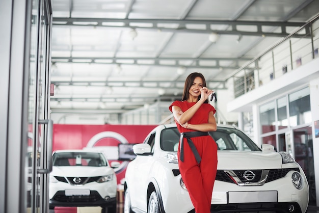 Sonriente vendedora de autos entregando las nuevas llaves del auto, el concesionario y el concepto de ventas. Mujer feliz el comprador