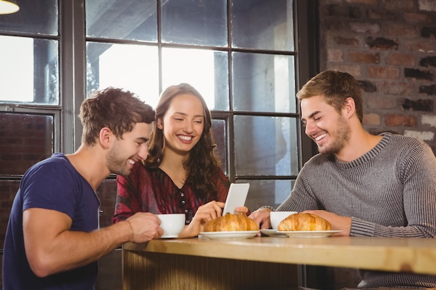 Sonrientes amigos disfrutando de café y cruasanes juntos