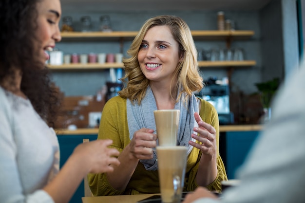 Sonrientes amigos tomando una taza de café frío en la cafetería