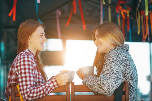 Sonrientes chicas jóvenes tomando café