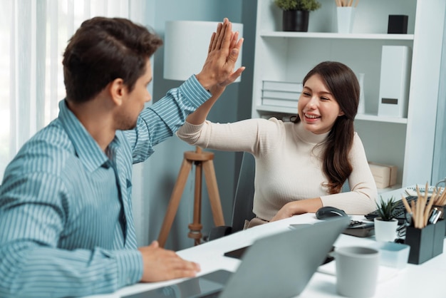 Sonrientes y felices compañeros de trabajo dando un "high five" levantando el puño del postulado de éxito.