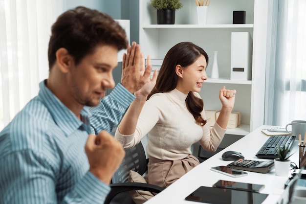 Sonrientes y felices compañeros de trabajo dando un "high five" levantando el puño del postulado de éxito.