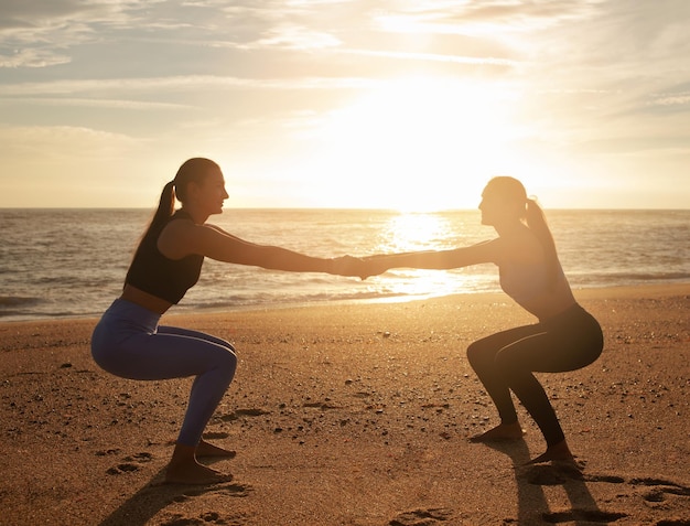 Sonrientes gemelas caucásicas milenarias hermanas mujeres sentadillas hacer ejercicios de piernas entrenamiento para el cuidado del cuerpo en