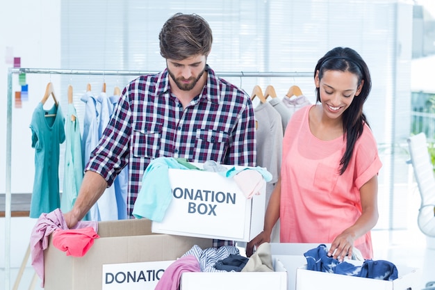 Sonrientes jóvenes amigos voluntarios separando la ropa