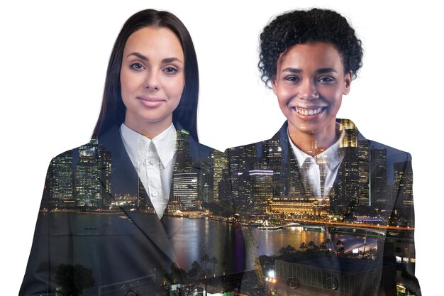 Sonrientes mujeres de negocios afroamericanas y europeas miran directamente a la cámara Asia estilo de vida corporativo multinacional diversos jóvenes profesionales Vista nocturna de la ciudad de Singapur