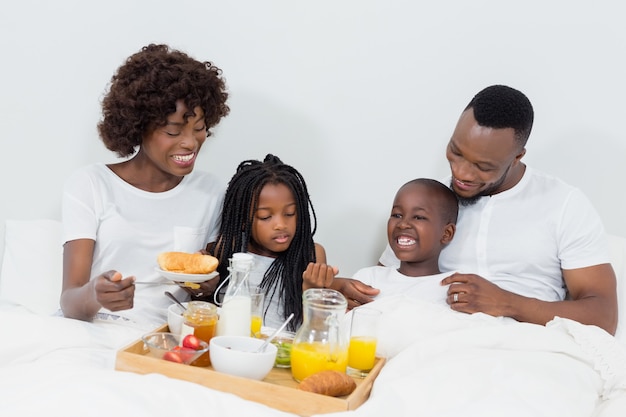 Sonrientes padres e hijos desayunando en la habitación