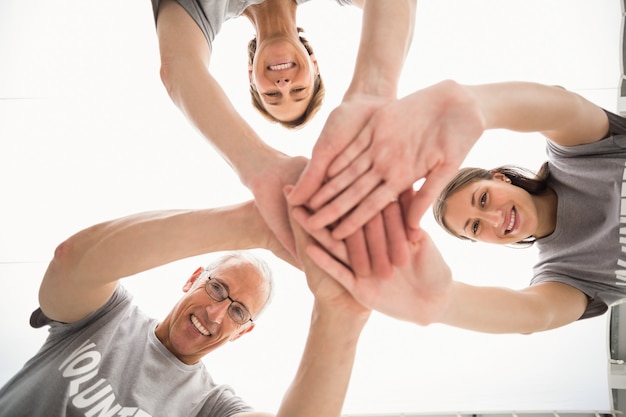 Sonrientes voluntarios juntando las manos