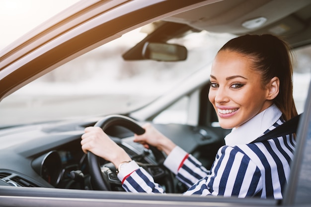 Foto sonrió magníficamente joven mujer sentada en el coche.