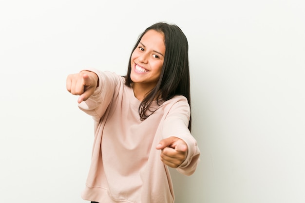 Sonrisa alegre de la mujer hispánica linda joven del adolescente que señala al frente.