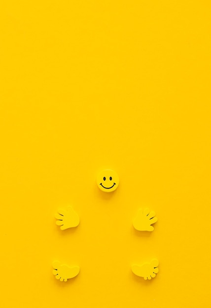 Sonrisa amarilla con manos y piernas sobre fondo amarillo.