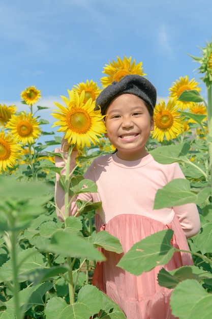 Sonrisa asiática linda de la muchacha con la flor del girasol