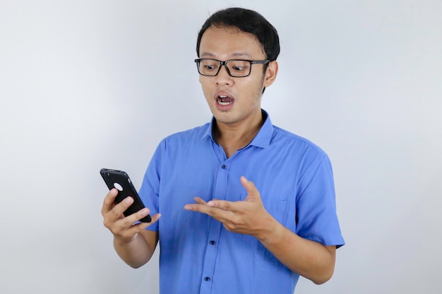 Sonrisa y cara feliz de un joven asiático con teléfono en la mano Concepto de modelo publicitario con camisa azul