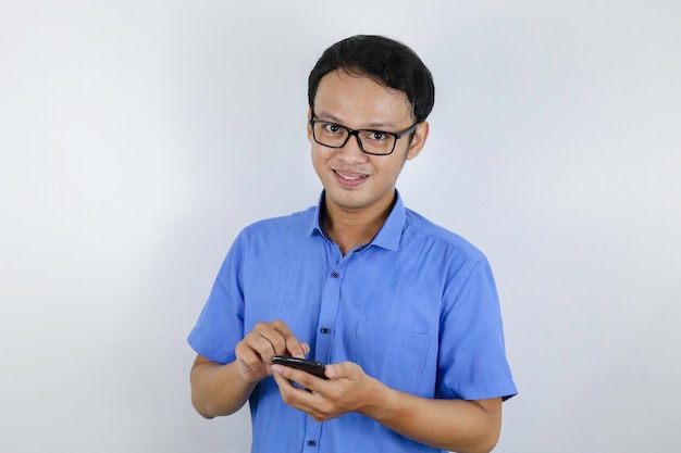 Sonrisa y cara feliz de un joven asiático con teléfono en la mano Concepto de modelo publicitario con camisa azul