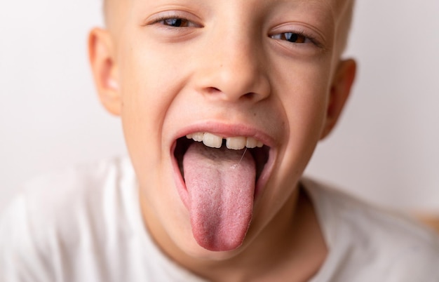 Sonrisa de clausura de un niño feliz de 8 años que muestra la lengua